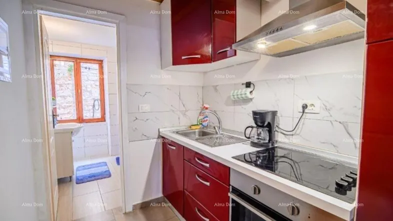 Moderne Küche mit roten Schränken, weißen Fliesen und Blick in ein angrenzendes Badezimmer.