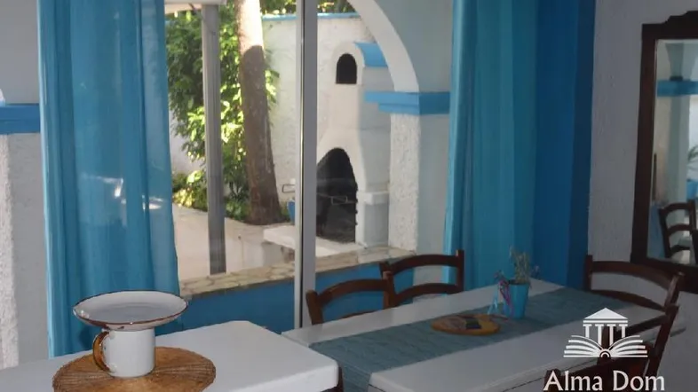 Gemütlicher Essbereich mit blauen Akzenten und Blick auf den Außenbereich mit Grill.
