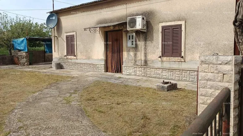Einfaches Einfamilienhaus mit beiger Fassade, Fensterläden und einem Vorgarten.