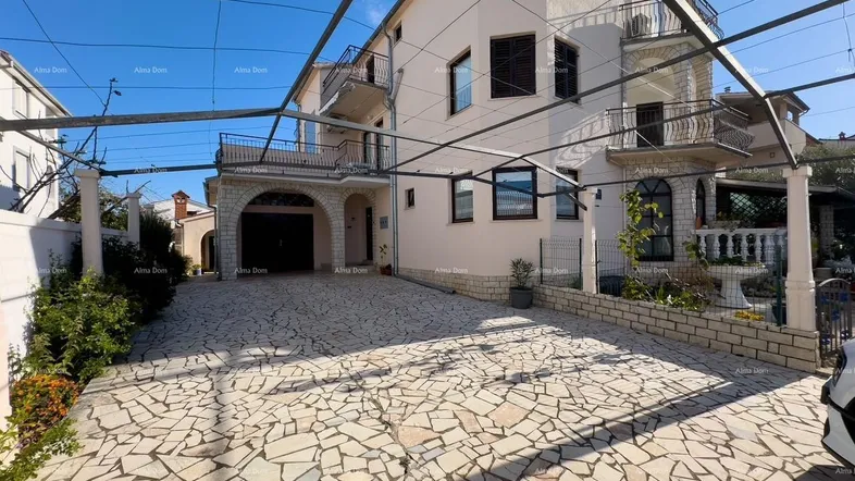Die Fassade des Hauses mit gepflasterter Auffahrt und integrierter Garage unter einem Bogen.