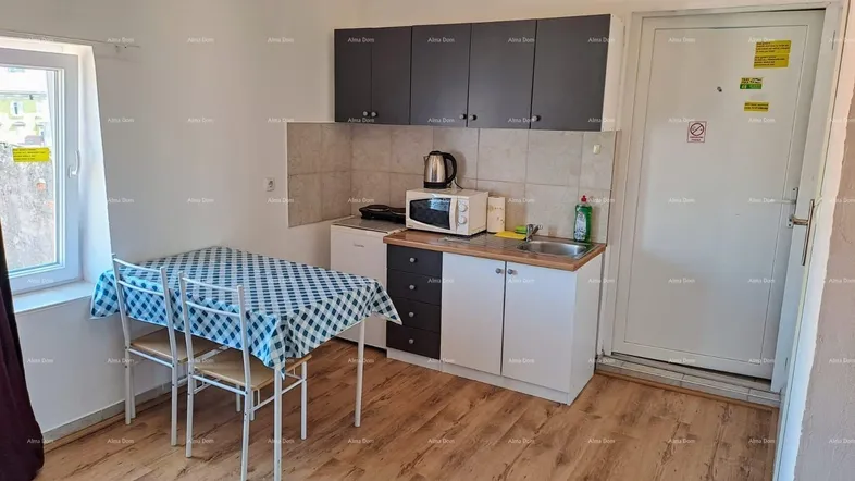 Kleine Küchenzeile mit Esstisch, Mikrowelle und Kühlschrank, ideal für einfache Mahlzeiten.