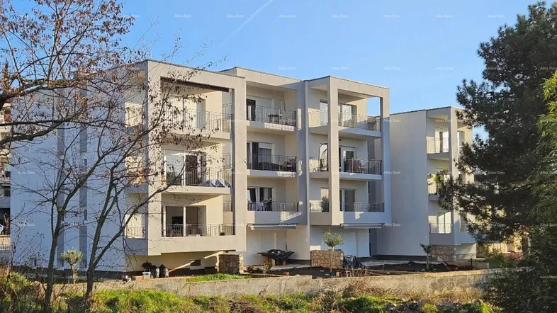 Modernes Mehrfamilienhaus mit mehreren Balkonen und großen Fenstern unter blauem Himmel.