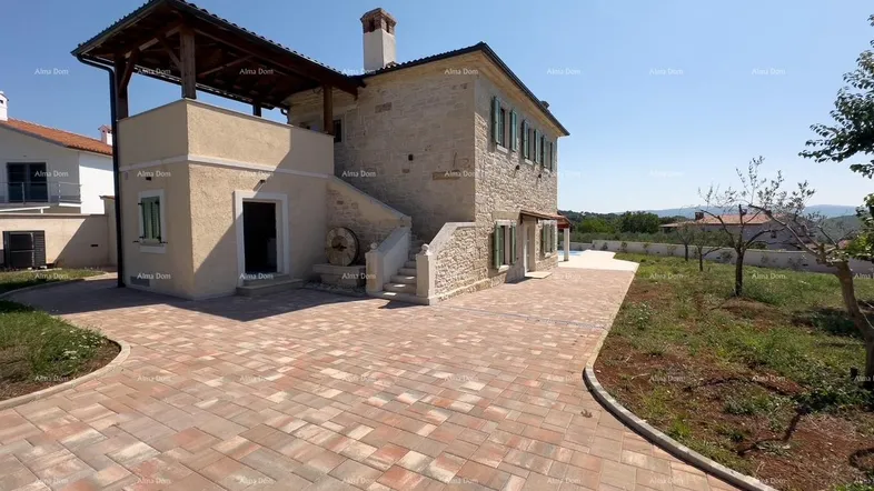 Traditionelles Steinhaus mit gepflastertem Vorplatz und mediterranem Flair unter blauem Himmel.