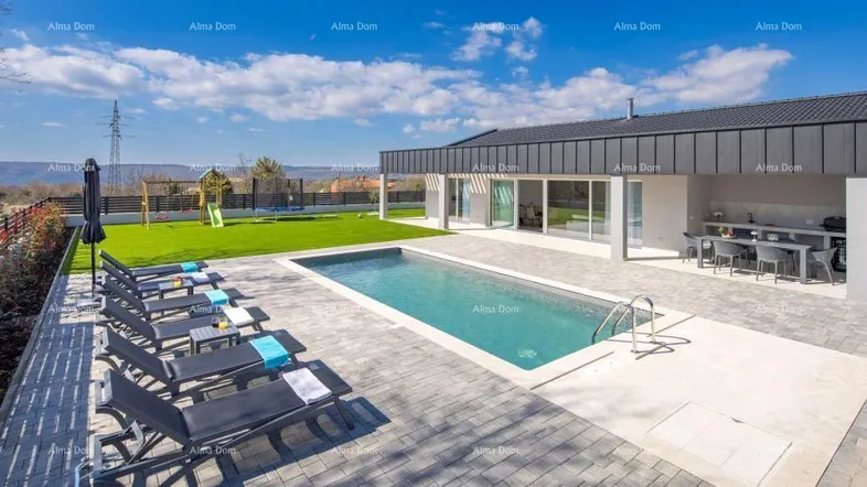 Großer Außenbereich mit modernem Pool, Liegestühlen und weitläufiger Rasenfläche unter blauem Himmel.