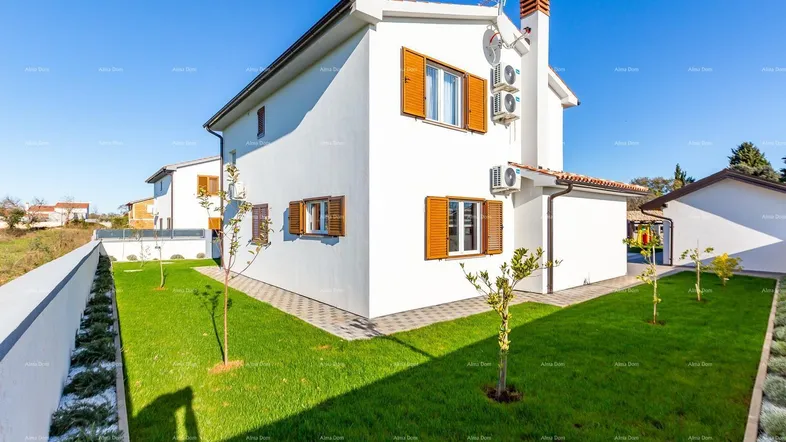 Weißes Haus mit braunen Fensterläden und gepflegtem Rasen im sonnigen Gartenbereich.