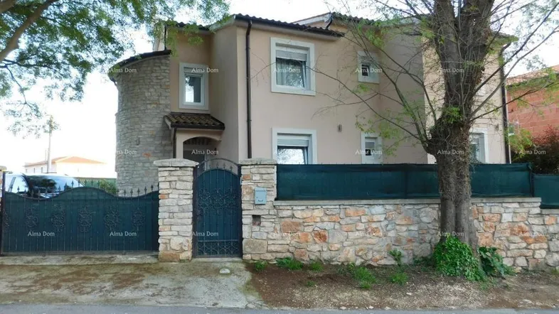 Traditionelles Haus mit Steinfassade und schmiedeeisernem Tor, umgeben von Bäumen.
