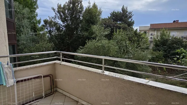 Geräumiger Balkon mit Fliesenboden, Metallgeländer und Blick ins Grüne unter bewölktem Himmel.