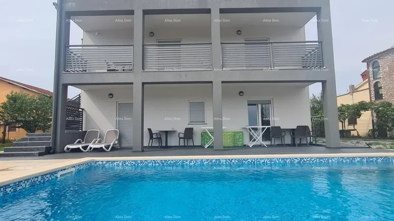 Modernes Apartmentgebäude mit mehreren Balkonen und einem großen Swimmingpool im Vordergrund.