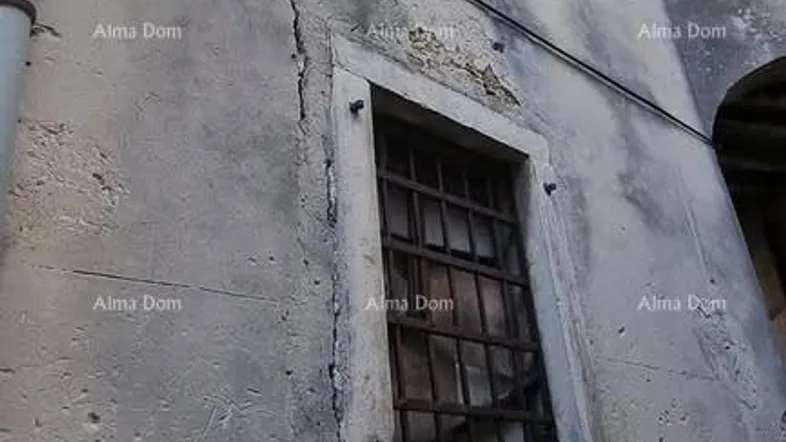 Altes Gebäude mit Steinfundament und verputzten Wänden, zeigt Fenster mit Fensterläden und Gitter.