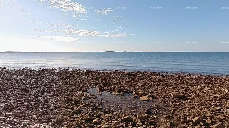 Felsiger Strandabschnitt am Meer unter blauem Himmel mit Blick auf die weite Wasserfläche.