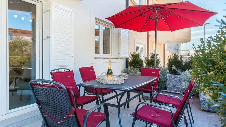 Gemütliche Terrasse mit Esstisch, roten Stühlen und Sonnenschirm, ideal für Mahlzeiten im Freien.