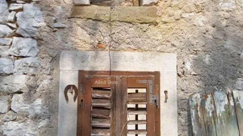 Altes Steingebäude mit verwitterten Holzfensterläden und einem kleinen, offenen Fenster darüber.