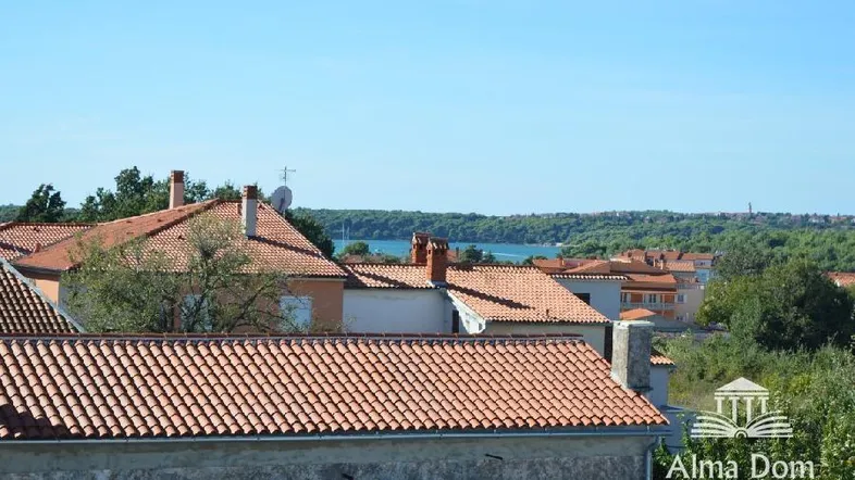 Blick über die Dächer der Stadt auf das Meer und die grüne Landschaft in der Ferne.