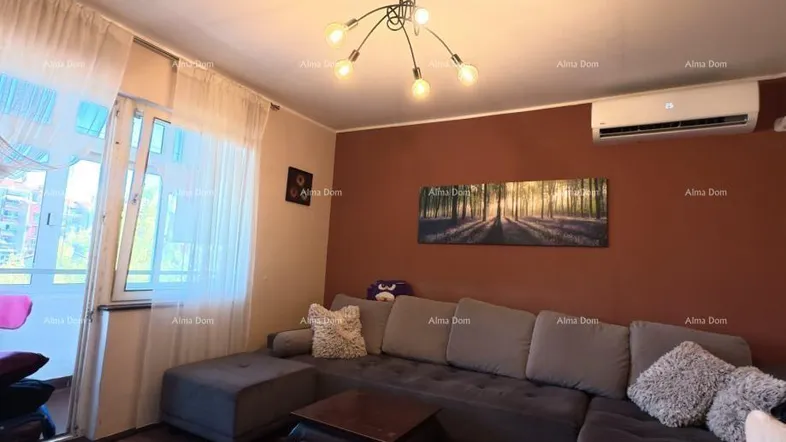 Gemütliches Wohnzimmer mit großem Ecksofa, Klimaanlage und Zugang zu einem Balkon.