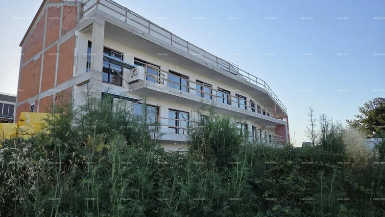 Neubau im Rohbauzustand mit sichtbaren Balkonen und Gerüst unter klarem Himmel.