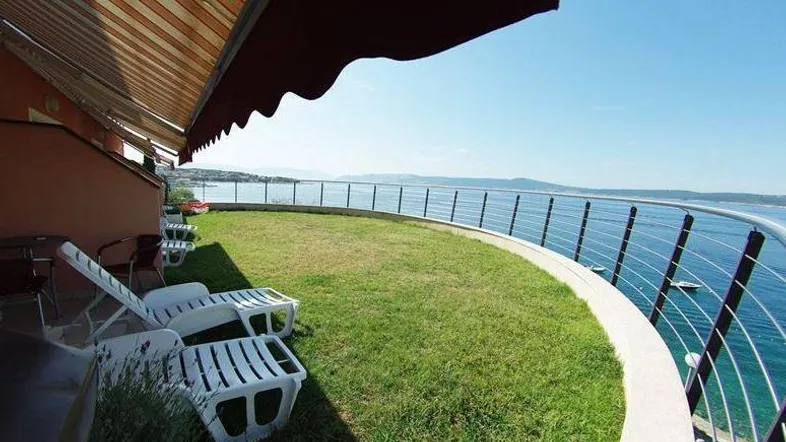 Große Rasenfläche mit Liegestühlen und Markise, direkt am Meer gelegen mit weitem Meerblick.