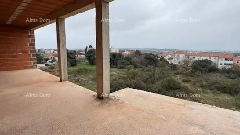 Unfertiger Balkonbereich mit Blick auf die umliegende Landschaft und Wohngebäude im Rohbauzustand.