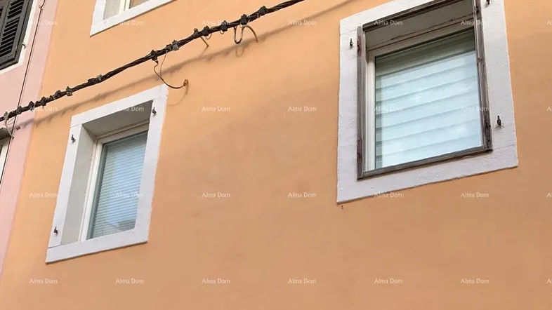 Fassade eines Gebäudes mit zwei Fenstern, Jalousien und einer alten Verkabelung.