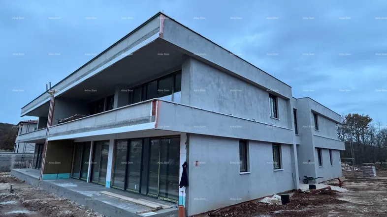 Modernes Gebäude im Bau mit großen Fenstern und Balkonen, umgeben von Baustelle.