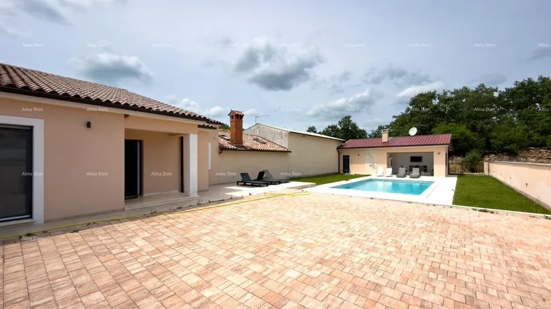 Außenansicht eines Hauses mit großem gepflasterten Bereich, Swimmingpool und Liegestühlen.