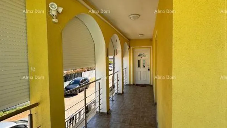 Langer, überdachter Balkon mit gelber Fassade und Blick auf die Straße.