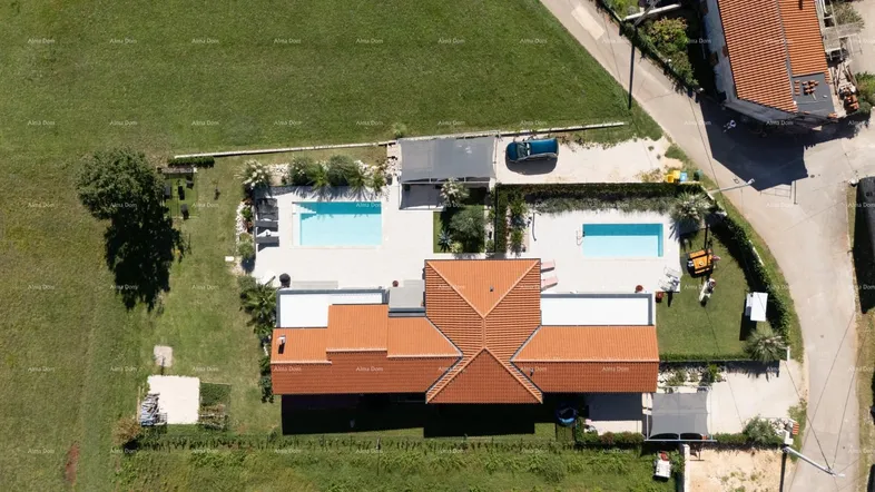 Luftaufnahme des Anwesens mit zwei Pools, großzügigen Grünflächen und umliegender Bebauung.