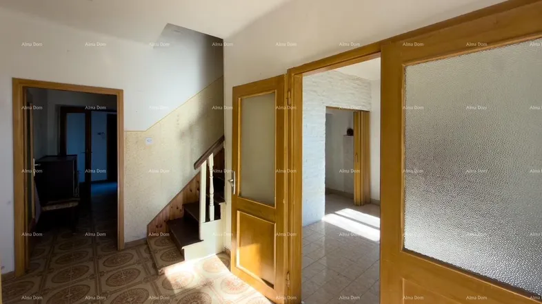 Heller Flur mit gemusterten Fliesenboden und Holztüren, der zu weiteren Räumen und einer Treppe führt.