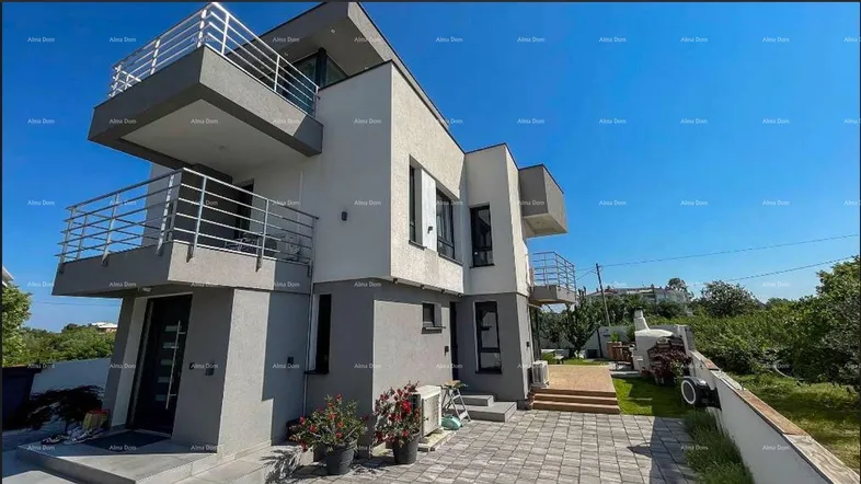 Moderne Villa mit mehreren Balkonen, gepflastertem Außenbereich und Garten.