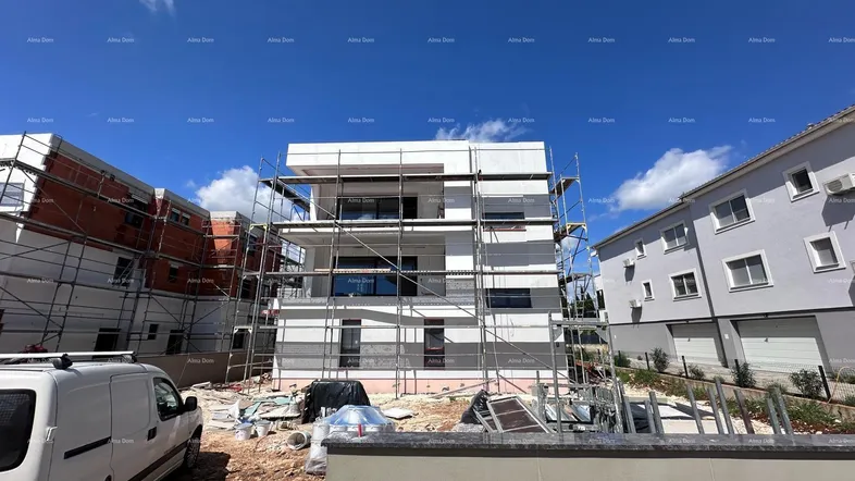 Neubauwohnung im Bau mit Gerüst an der Fassade und Baufahrzeug im Vordergrund.