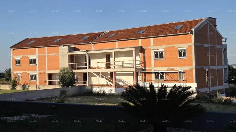 Neubau im Rohbauzustand mit Ziegelmauerwerk und Dachziegeln unter klarem Himmel.