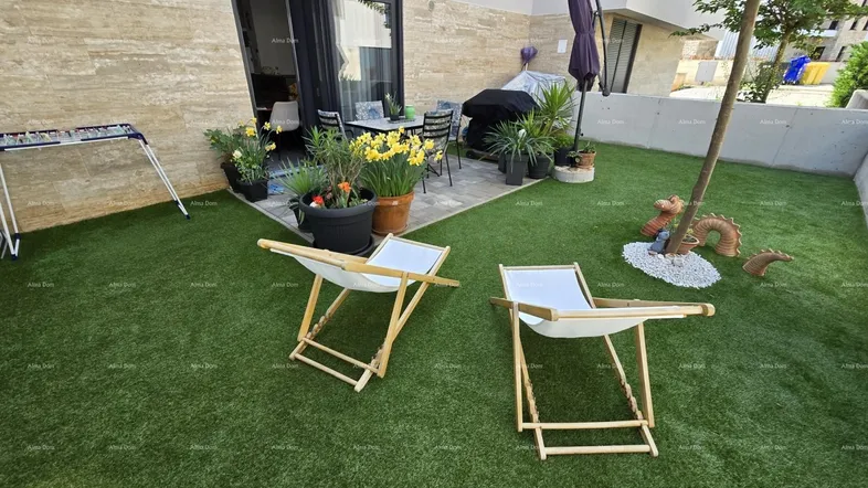 Gepflegter Gartenbereich mit Kunstrasen und einer möblierten Terrasse für entspannte Stunden im Freien.
