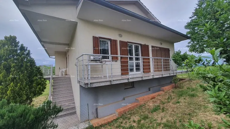 Ansicht des Hauses von der Seite mit Balkon und Außentreppe, umgeben von grüner Landschaft.