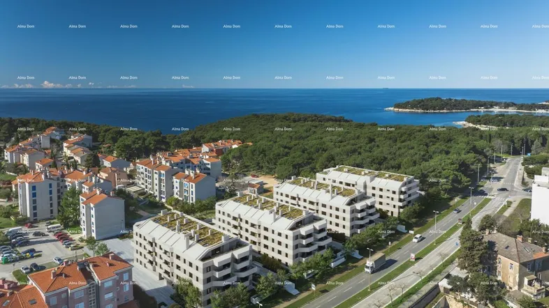 Luftaufnahme moderner Apartmentgebäude mit begrünten Dächern und Meerblick in einer Küstenstadt.