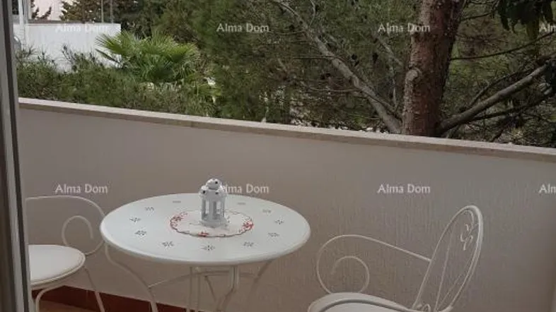 Gemütlicher Balkon mit weißem Tisch und Stühlen, umgeben von grünen Bäumen.