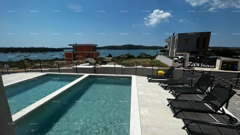 Geräumiger Außenbereich mit zwei Pools, Liegestühlen und weitem Meerblick unter blauem Himmel.