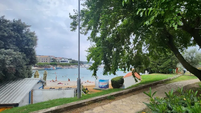 Panoramablick auf den Strand mit Badegästen und das Meer unter bewölktem Himmel.