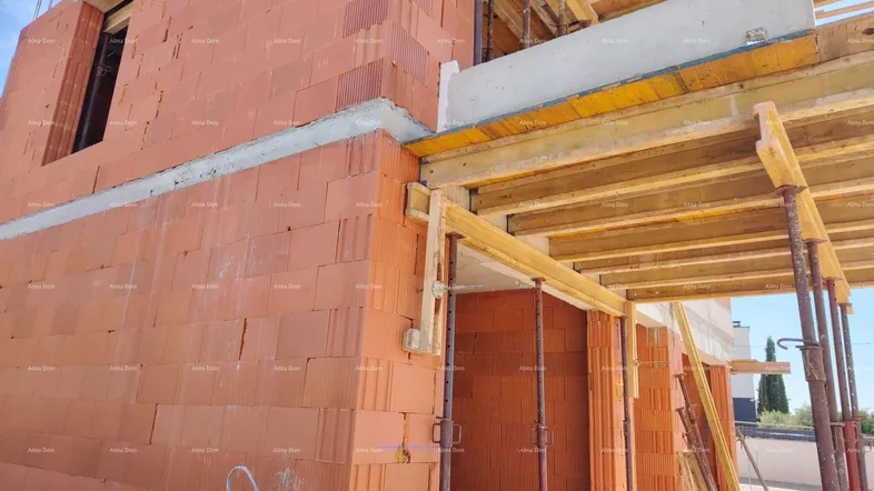 Rohbau eines Gebäudes mit Ziegelwänden und Gerüst, bereit für weitere Bauarbeiten.