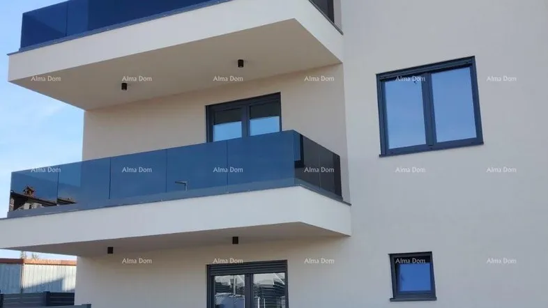 Modernes Mehrfamilienhaus mit mehreren Balkonen und Glasgeländern unter blauem Himmel.