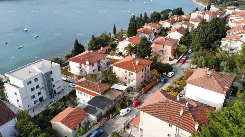 Luftaufnahme einer Küstenstadt mit zahlreichen Häusern, umgeben von üppiger Vegetation und dem Meer.