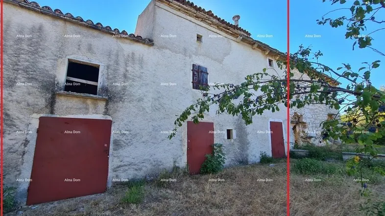 Altes Steinhaus mit verputzter Fassade und roten Türen, umgeben von trockener Vegetation unter blauem Himmel.