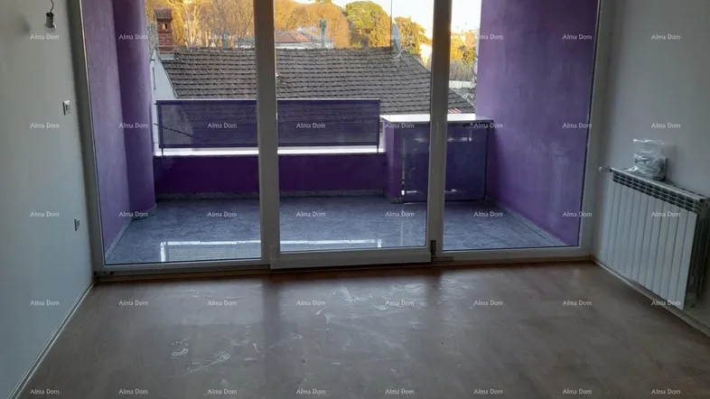 Helles Zimmer mit Holzboden, Zugang zu einem Balkon und Blick ins Grüne.