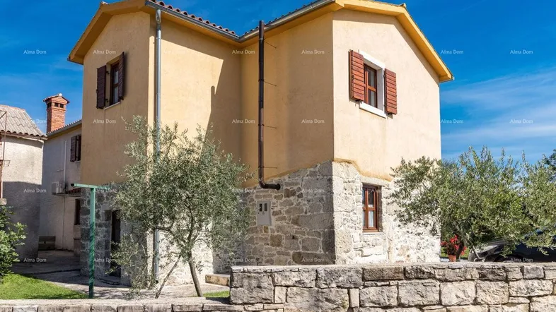 Traditionelles Haus mit Steinfassade und gelbem Putz unter blauem Himmel.