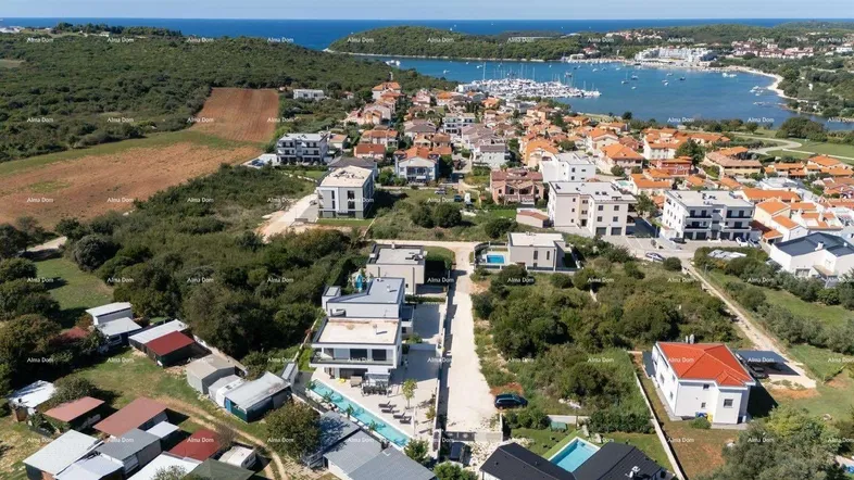 Luftaufnahme einer modernen Wohnsiedlung mit Meerblick und Yachthafen in der Ferne.