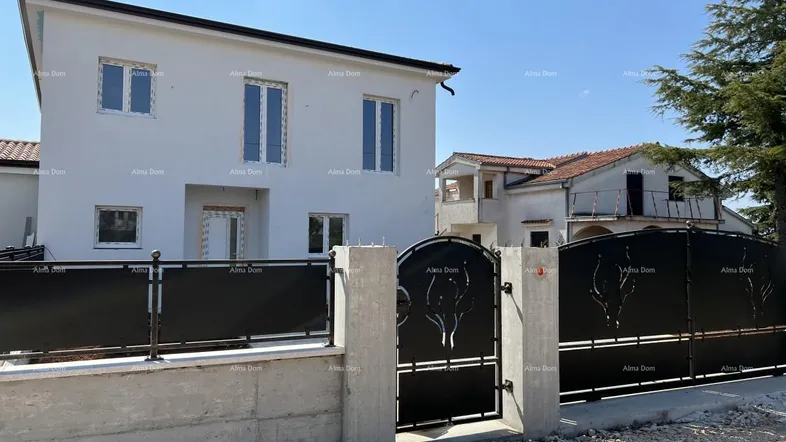 Vorderansicht eines modernen Neubaus mit weißer Fassade und einem dekorativen Eingangstor.