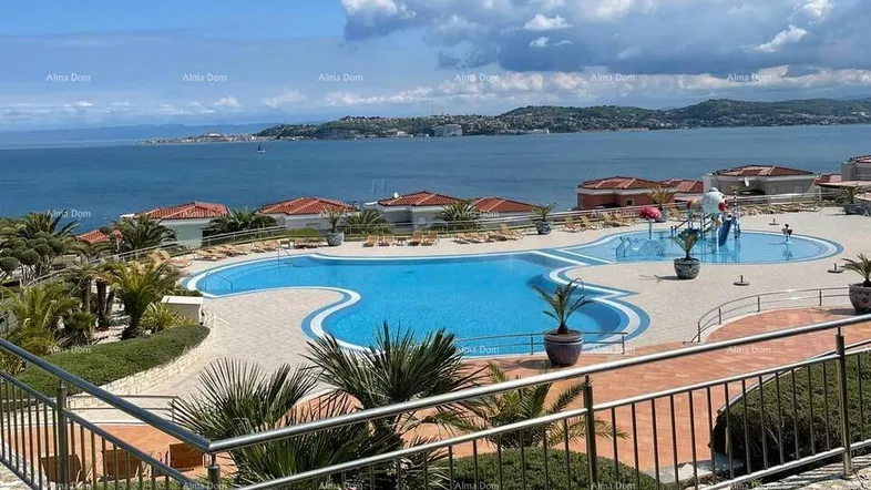Großer Gemeinschaftspool mit Meerblick und Liegebereichen in einer gepflegten Anlage.
