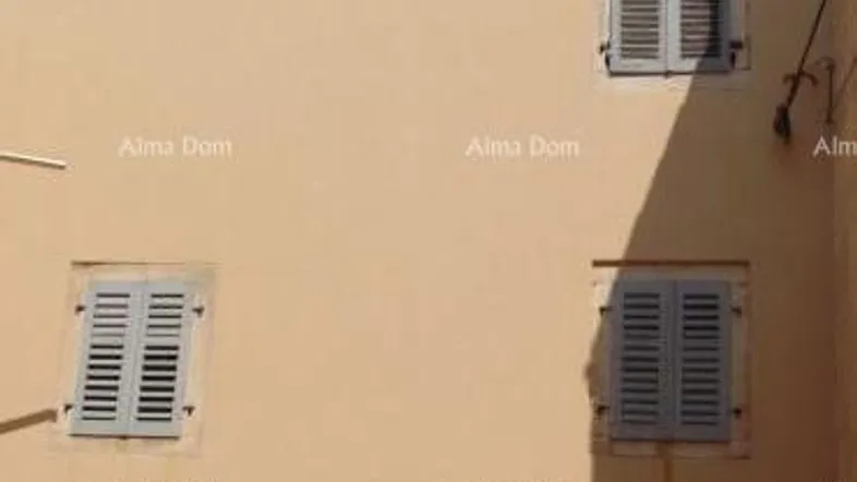 Fassade eines traditionellen Gebäudes mit hellen Wänden und Fensterläden unter blauem Himmel.