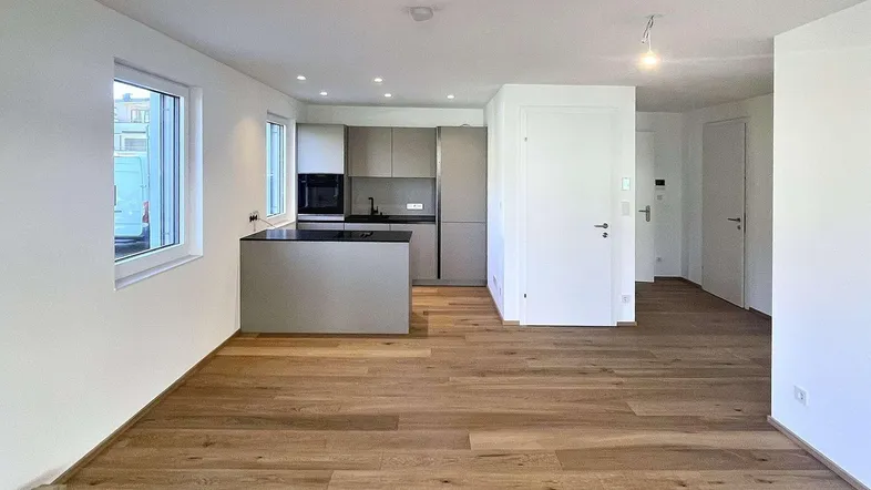 Heller, offener Wohn- und Essbereich mit moderner Einbauküche und Holzboden.
