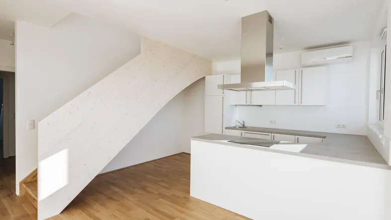 Moderne offene Küche mit Holzboden und integrierter Treppe, die zu einem weiteren Stockwerk führt.