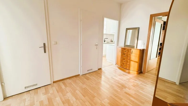 Heller Flur mit Parkettboden, weiß gestrichenen Wänden und Zugang zu weiteren Räumen.