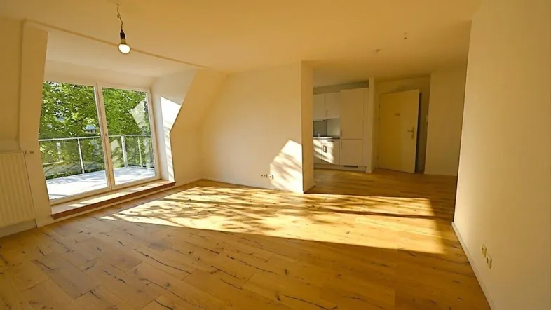 Helles Wohnzimmer mit Holzboden, Zugang zum Balkon und viel natürlichem Licht.